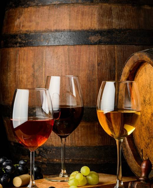 Tree wineglasses with grapes on wooden barrel background